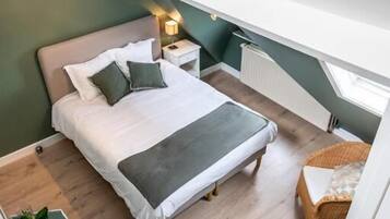 A bedroom with a bed, bedside tables, a radiator, a window, and a staircase.