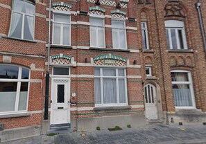 En flerplansbygning i mursten med hvidt rammevinduer og dekorative murstensdetaljer.