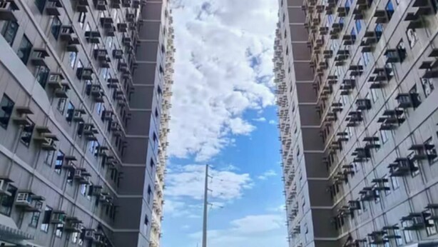 A modern residential building with a central swimming pool, surrounded by balconies and outdoor seating. - Lux 2BR Sky Condo With 24-hr Security, Fully Airconditoned & Basement Parking (Dasmarinas)