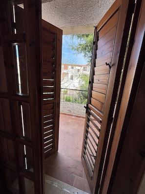 Eine Holztür, die auf einen Balkon mit Blick auf Gebäude und Bäume führt.