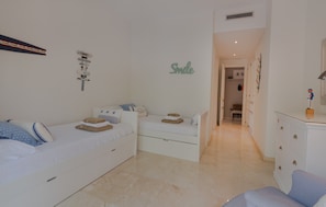 A bedroom with two beds, a dresser, and a wall with a 'Smile' sign. - Elegant Seafront Retreat in Rio Real Playa (Marbella)