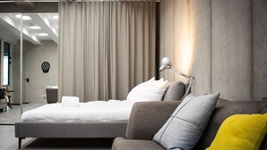 Een moderne hotelkamer met een groot bed, een bank, een lamp en een dartbord aan de muur.