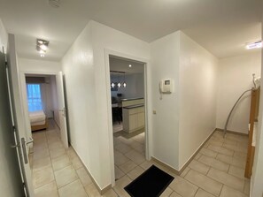 Een hotelkamer met een bed, een klein bureau, een badkamer met douche en een kitchenette.
