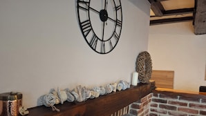 A rustic interior with a wooden mantel, a large wall clock, and a brick fireplace. - Country charm (Iviers)