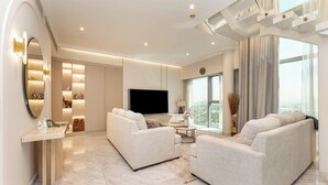 A modern living room with two sofas, a TV, and a large window offering a city view. - PVH - Central Park 1BR with Study Room (Dubai)