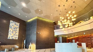 A modern lobby with a geometric floor pattern, a reception desk, and a large illuminated wall art piece. - PVH - Central Park 1BR with Study Room (Dubai)
