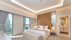 A modern bedroom with a large bed, a bedside table, a mirror, and a view of the city. - PVH - Central Park 1BR with Study Room (Dubai)