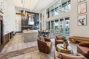 A spacious lobby with a bar area, seating, and large windows offering views of the outside. - Landing Apartments Fort Worth near Cultural District (Fort Worth)