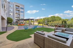 A courtyard with outdoor seating, a pergola, and a building with multiple floors. - Landing Apartments Fort Worth near Cultural District (Fort Worth)