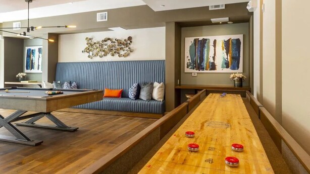 A billiards room with a pool table, a long table game, a blue sofa, and abstract art on the walls. - Landing Amazing 1bd, Courtyard, Game Room (Houston)