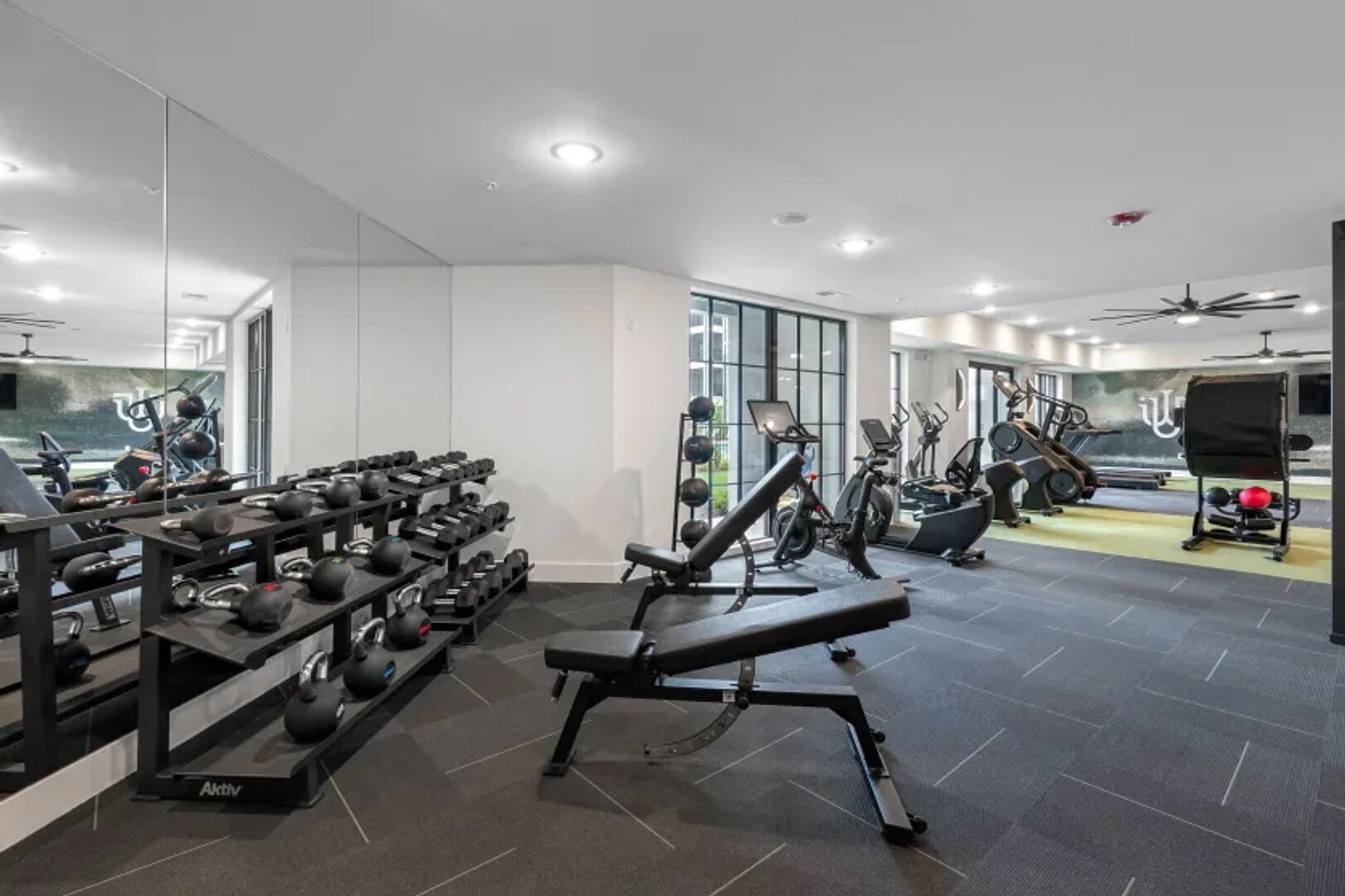 Een moderne sportschool met diverse trainingsapparaten, waaronder loopbanden, krachttoestellen en gewichten.