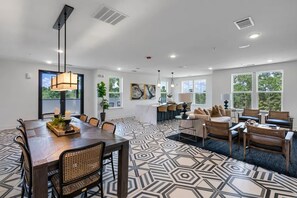 A spacious living area with a dining table, sofas, and a kitchen in the background. - Landing Furnished Apartments - Belville (Leland)