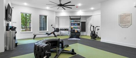A gym with exercise equipment, a ceiling fan, and a sign with rules.