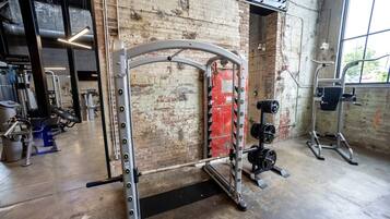 A gym with a squat rack, weight bench, and various exercise machines.