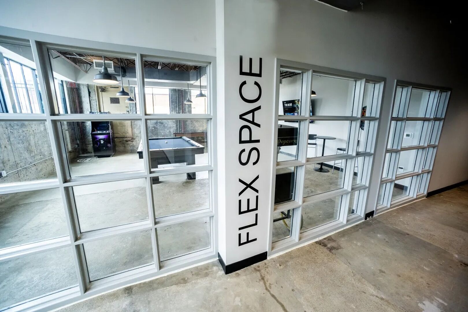 A room with large windows, a pool table, and a wall labeled 'FLEX SPACE'.