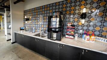 Una cocina moderna con una estación de café, un lavamanos y una pared decorativa con patrones circulares.