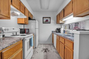 Une cuisine de taille réduite, dotée de meubles en bois, d’une cuisinière blanche, d’un four à micro-ondes et d’un évier.