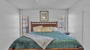 Un dormitorio con una cama de madera, un ventilador de techo y un cuadro en la pared.