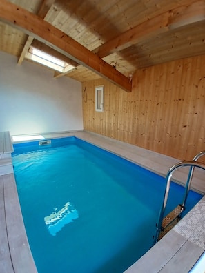 Ein Schwimmbecken mit Holzwänden und einer Metallleiter.