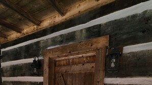 A rustic wooden door with a metal latch, set in a log cabin with horizontal wooden planks on the walls and a wooden floor. - Whispering Pine's Cabin! NO CHECK-OUT LIST (Patriot)
