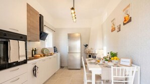 Eine moderne Küche mit Kühlschrank, Ofen und einem Essbereich mit Tisch und Stühlen.