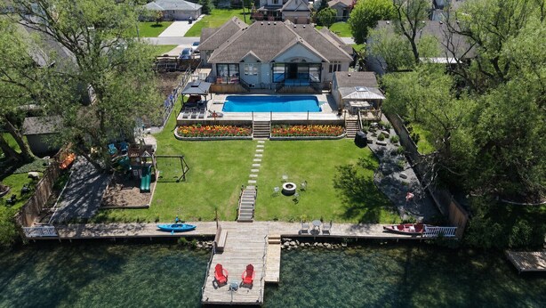 Luchtbeeld van een woonhuis met zwembad, steiger en een terras.