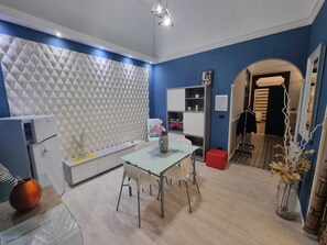 Une cuisine moderne aux couleurs blanche et bleue, comprenant une table à manger, des chaises et un meuble de rangement intégré, également blanc.