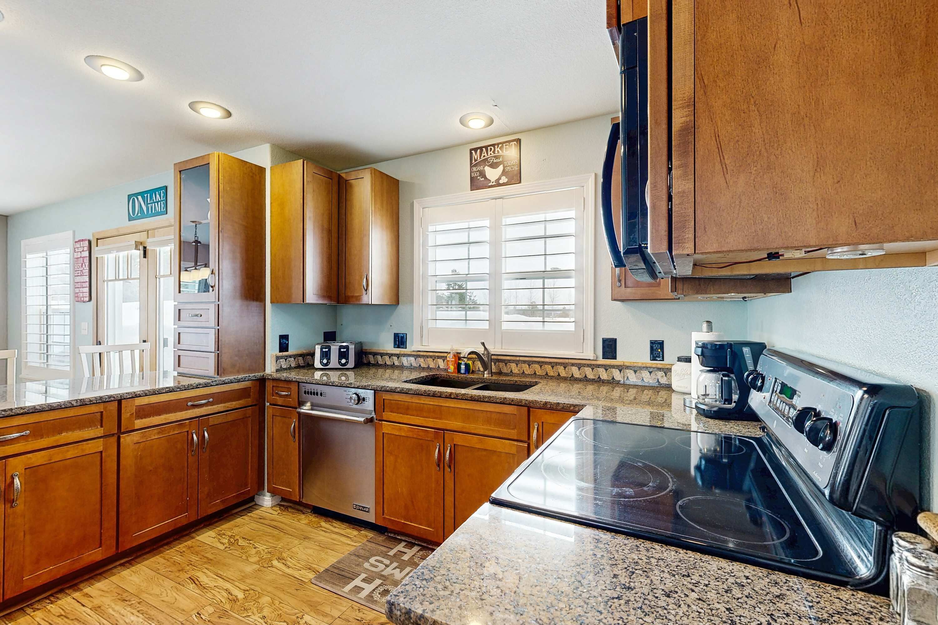 A kitchen with wooden cabinets, a stove, a dishwasher, and a coffee maker.