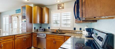 A kitchen with wooden cabinets, a stove, a dishwasher, and a coffee maker.