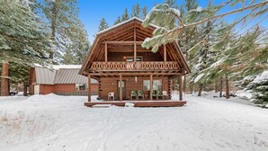 Een houten hut met een balkon, omringd door met sneeuw bedekte bomen.