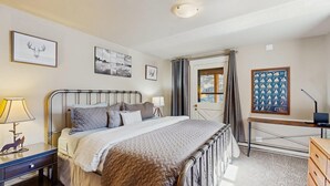 Een slaapkamer met een bed, nachtkastjes, een bureau en een raam.