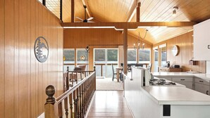 Uma cozinha moderna com uma ilha grande, painéis de madeira e vista para um lago.