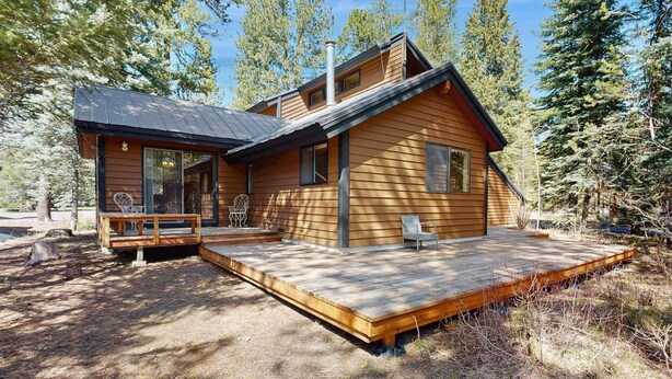 Une cabane dotée d’une terrasse, d’un porche couvert et d’une cheminée.