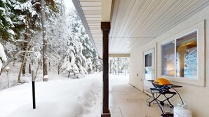 Ein überdachter Außenbereich mit Grill und Propangasflasche, umgeben von schneebedeckten Bäumen.