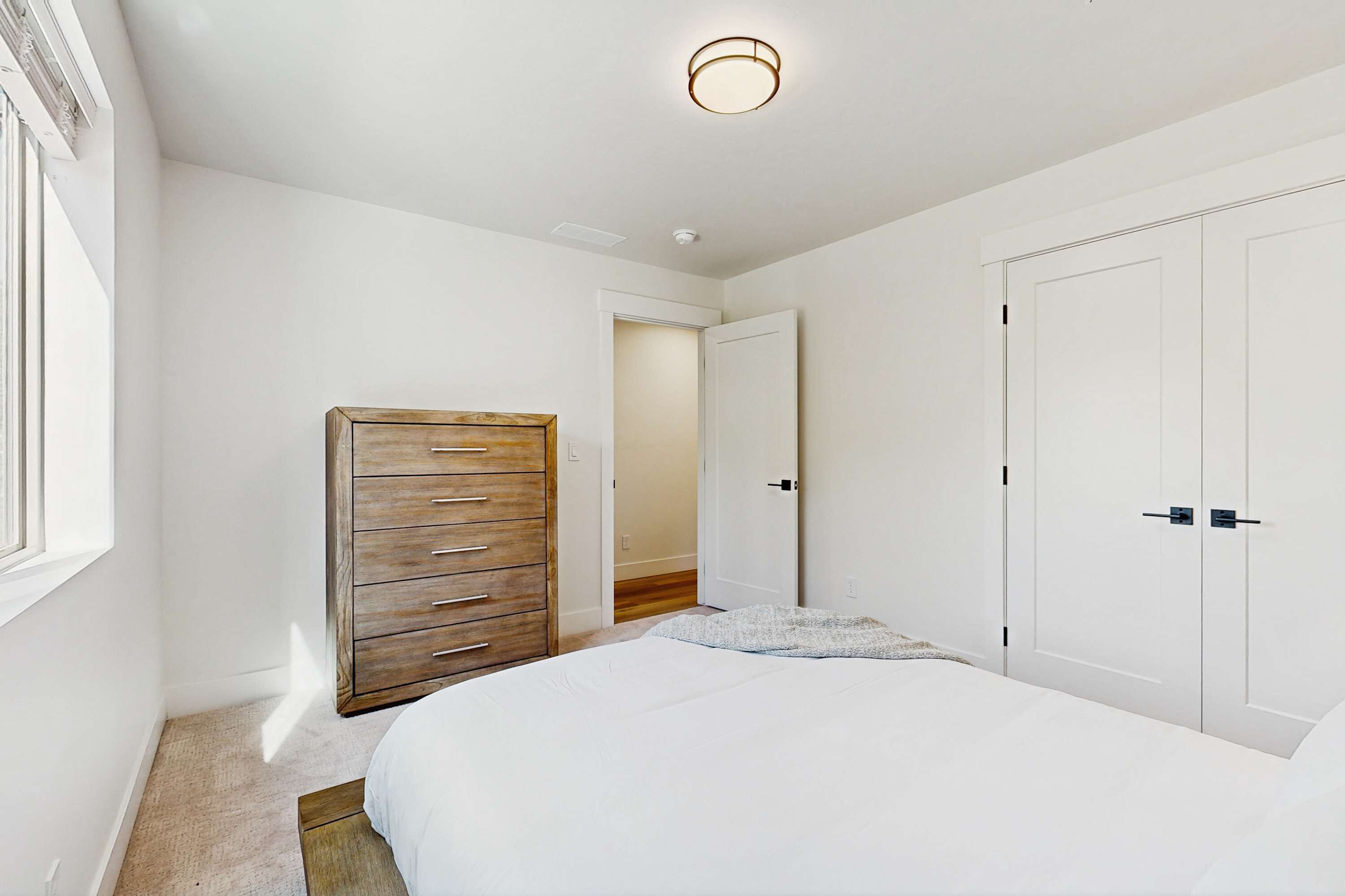 Une chambre à coucher avec un grand lit, une commode en bois et des armoires blanches.
