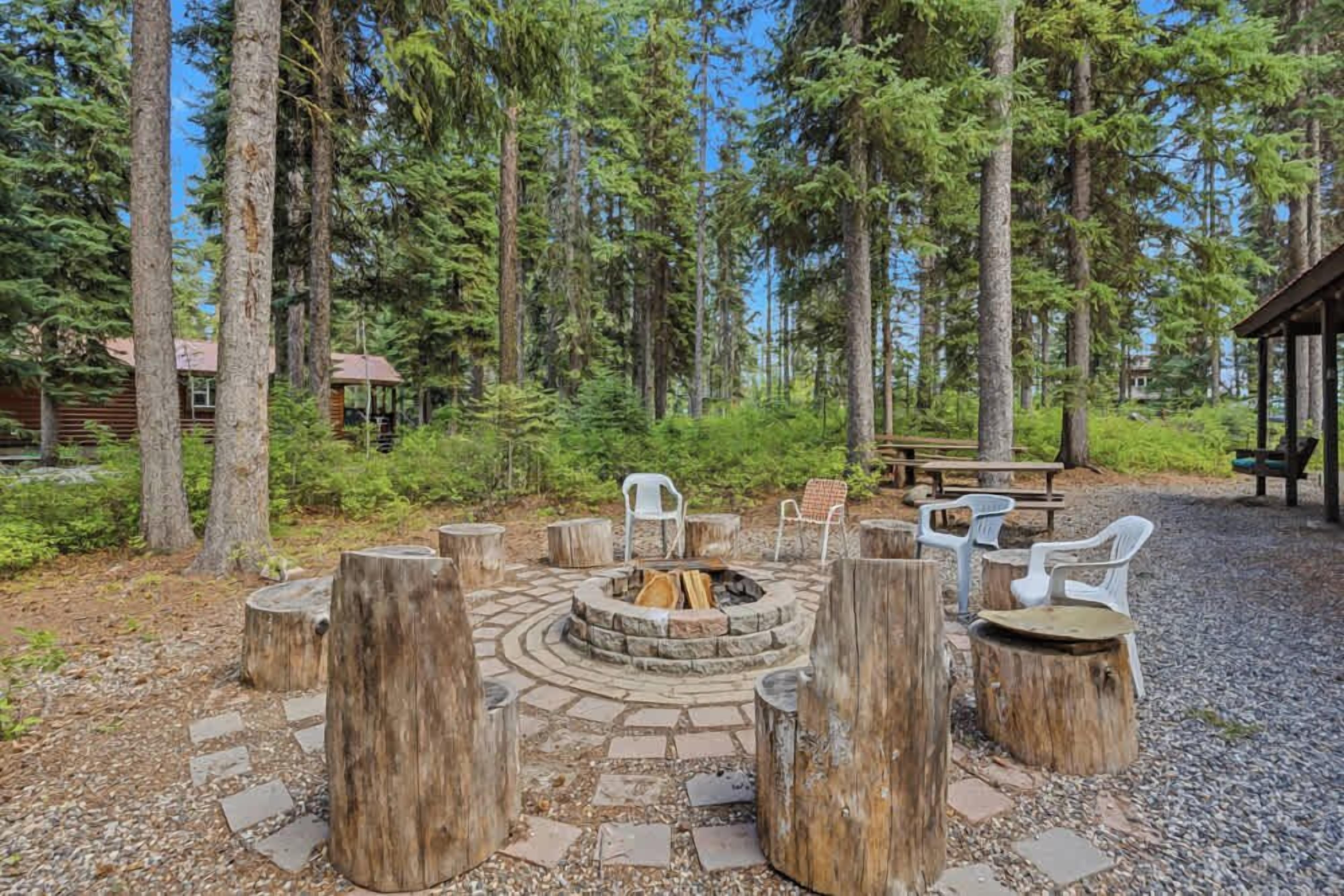 A circular fire pit with seating around it, surrounded by trees.