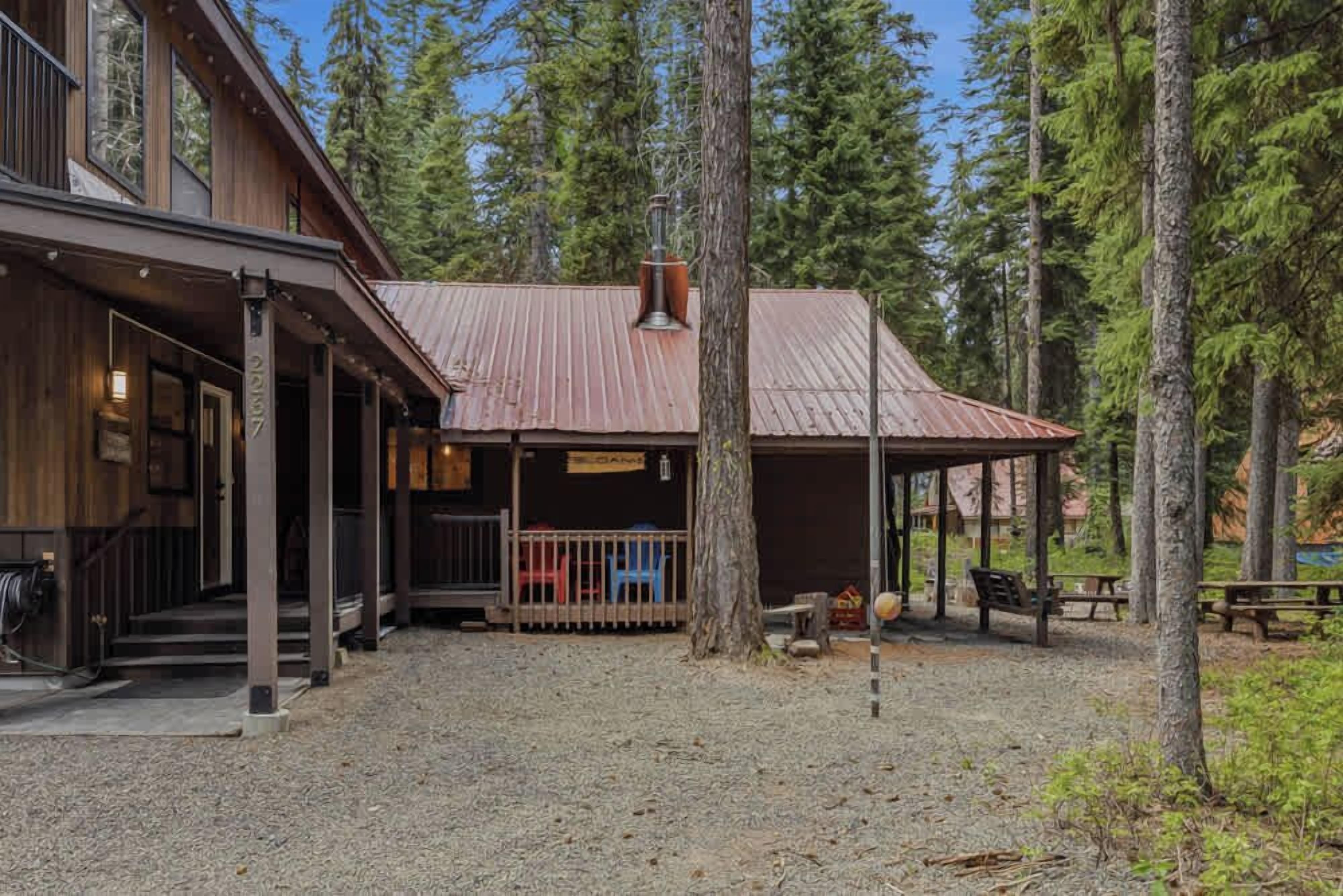 A rustic cabin with a metal roof, surrounded by tall trees.