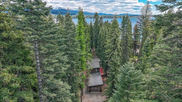A forested area with a cabin and a lake in the background. - Awesome Payette Lake Cabin, Fire Pit, Near Beach (McCall)