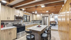 Une cuisine moderne avec des meubles en bois, des appareils en acier inoxydable et un îlot central doté de tabourets de bar.