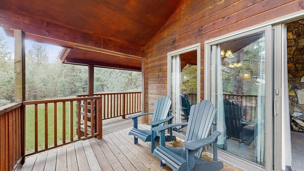 A wooden deck with Adirondack chairs, a glass door, and a stone wall. - Cascade Cabin | Deck, 2 Living Rooms + Fireplaces (Cascade)