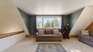 A loft-style room with a brown leather sofa, a patterned rug, and a bear statue.