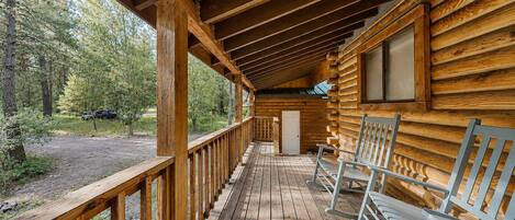 A wooden cabin with a porch, a window, and a door.