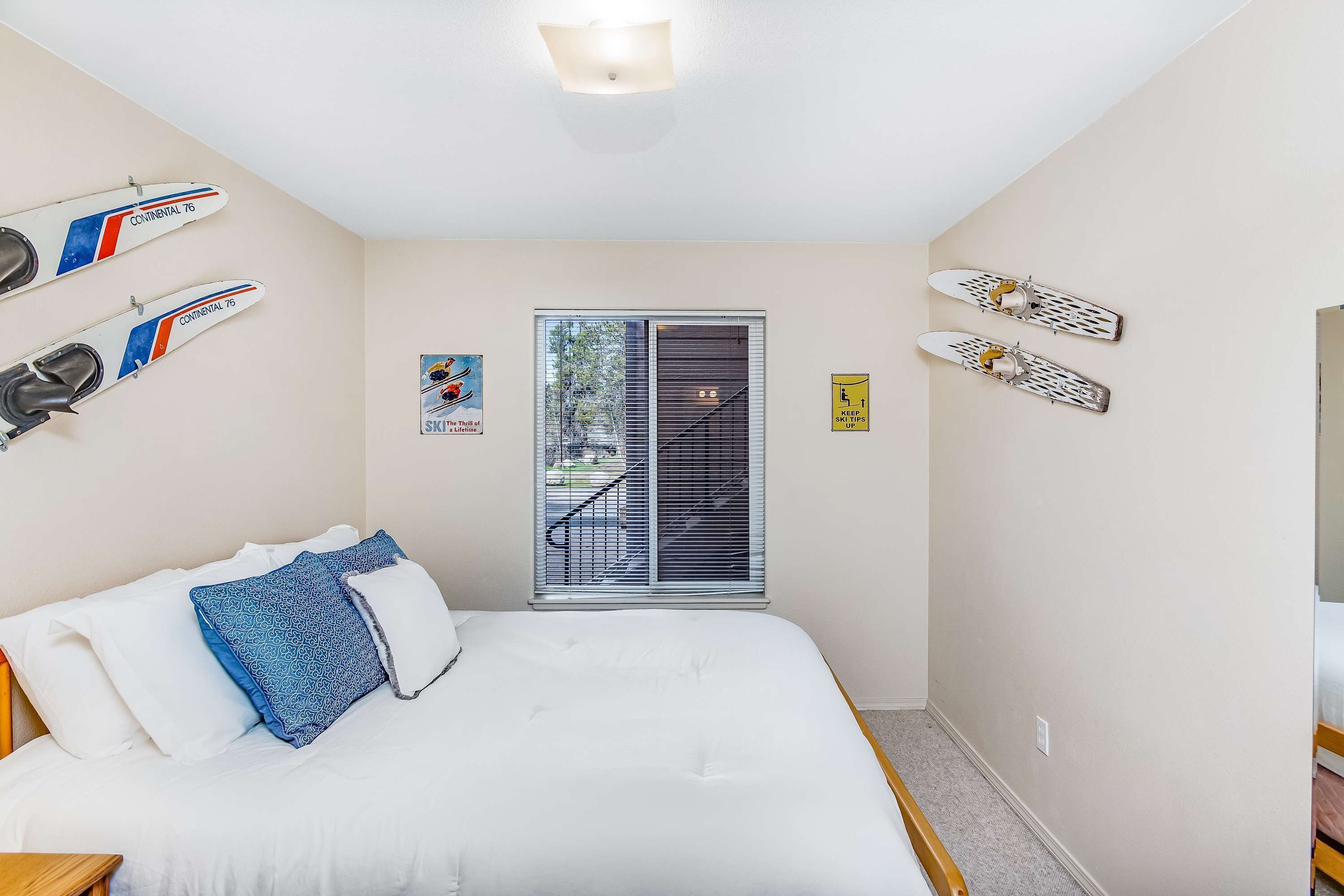 A bedroom with a bed, pillows, and two surfboards mounted on the wall.