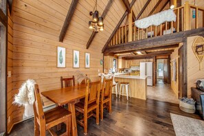 Un interior de madera con comedor, cocina y un altillo.