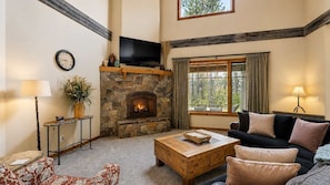 A living room with a stone fireplace, a flat-screen TV, a sofa, and a coffee table.