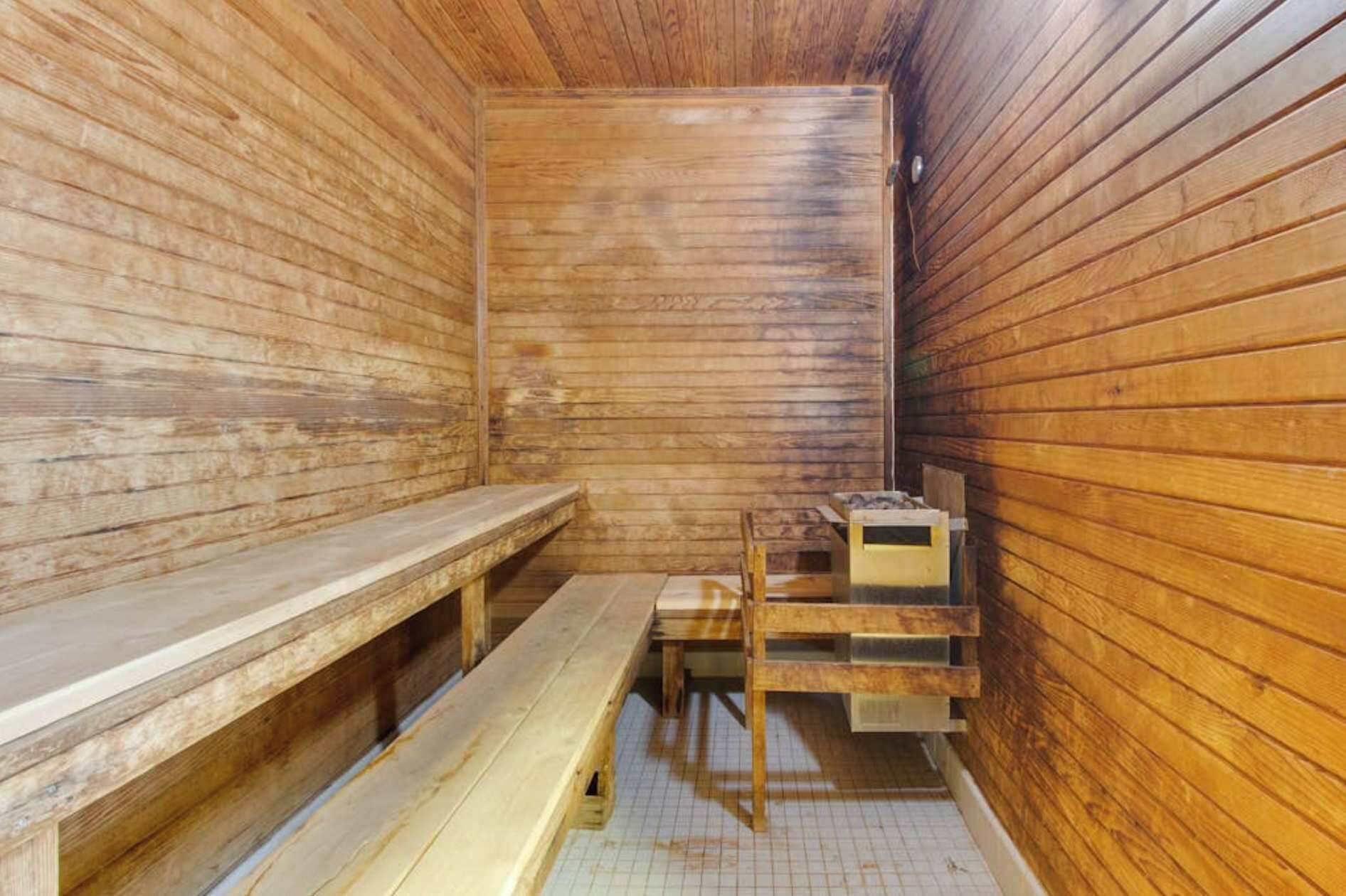 Een sauna met houten wanden, banken en een kleine tafel.