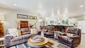 Uma sala de estar moderna com um sofá, duas poltronas, uma mesa de centro e um espaço de jantar com uma mesa e cadeiras.