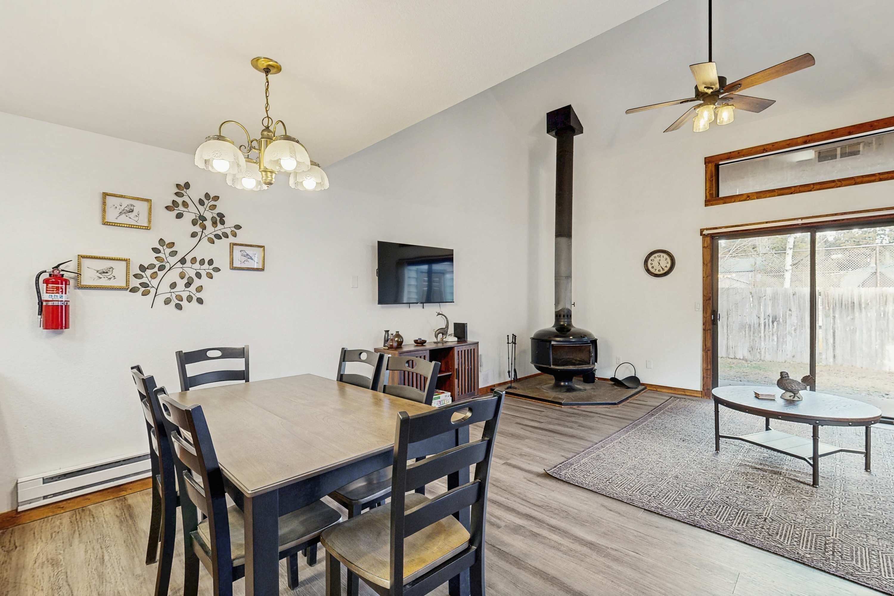A dining area with a wooden table and chairs, a fireplace, and a ceiling fan.