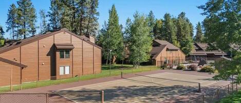Un quartier résidentiel comprenant plusieurs maisons, un court de tennis clôturé et un panneau indiquant : « Réservé aux propriétaires d’Aspen ».