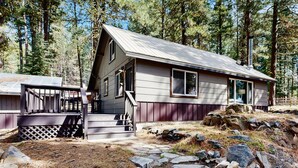 A cabin with a sloped roof, a porch with steps, and a stone foundation. - Downtown McCall Retreat | Wood Stove & Deck (McCall)